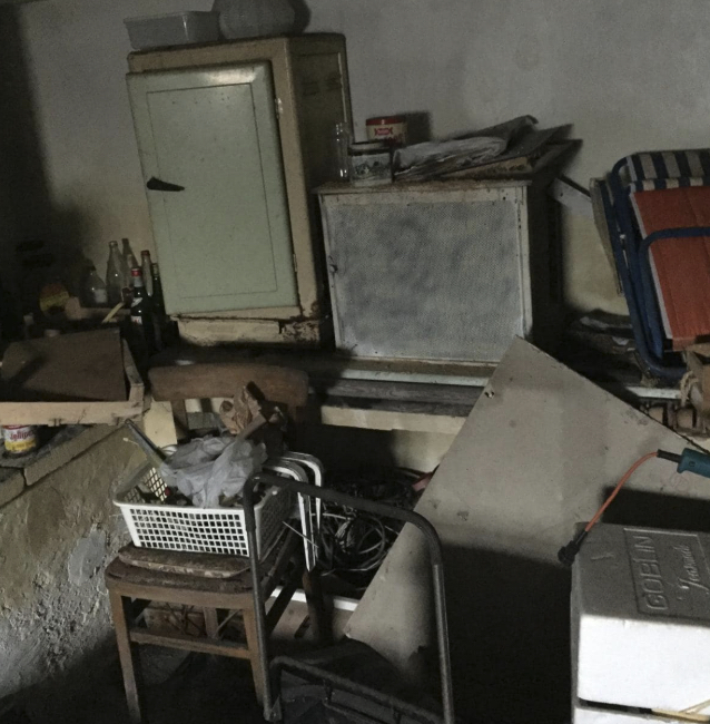 Old appliances and items piled in a dark room before clearance